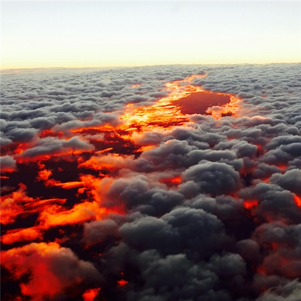 Cảnh hoàng hôn đỏ rực nhìn từ phía trên các đám mây ở Australia, giống như thể có ai vừa làm đổ lửa trên nền trời vậy.