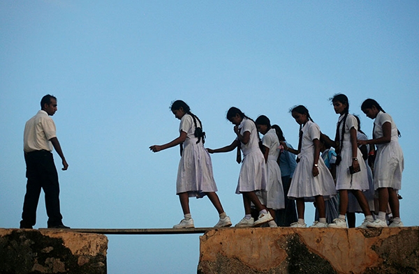 
	
	Những nữ sinh Sri Lanka đang băng qua một tấm ván gỗ mỏng đến đến trường. Ảnh: Reuters.