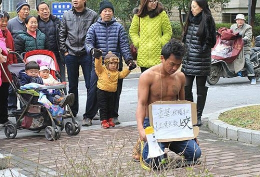 
	
	Wang quỳ gối trước khu nhà vợ chồng anh sống mong vợ tha lỗi vì không nộp lương 2 tháng. Ảnh: China.org.cn.
