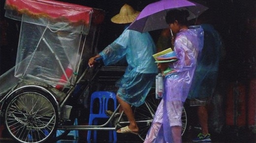 
	
	Tại cửa đền Bà Kiệu, một cô bé đi bán áo mưa cho khách du lịch.
