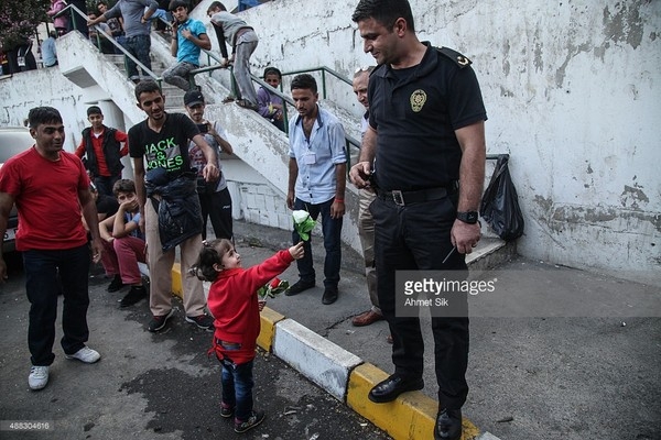 
Một hình ảnh rất đẹp của một cô bé trong đoàn người tị nạn tặng một bông hoa cho người cảnh sát Thổ Nhĩ Kỳ đang làm nhiệm vụ trấn át dân tị nạn biểu tình. Con số người tị nạn không có đồ ăn, thức uống và mắc phải những bệnh dịch nguy hiểm đã lên đến hàng nghìn người, khi mà chính phủ Thổ Nhĩ Kỳ không cho phép bán vé xe bus tới biên giới khiến họ phải chờ đợi rất nhiều ngày tại nhà ga trong vô vọng. (Ảnh Internet)