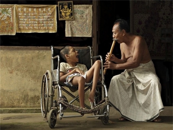 
Bali: Người đàn ông thổi sáo bên cạnh cậu bé tàn tật mà ông yêu quý như đứa con ruột thịt.