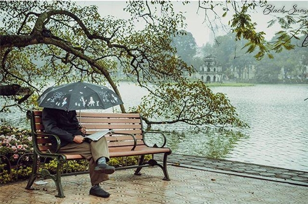 
Buổi sáng trời mưa nhẹ cùng chiếc ô nhỏ và tờ báo, nơi góc bờ hồ... cuộc sống dung dị của người dân Thủ đô. (Ảnh: Instagram)
