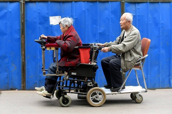 
Nhưng những năm gần đây, sức khỏe không cho phép ông đi đoạn đường xa như vậy. Vì thế, ông sửa cấu tạo chiếc xe lăn lại một chút để có thể bên cạnh vợ mình mọi nơi. (Ảnh Internet)