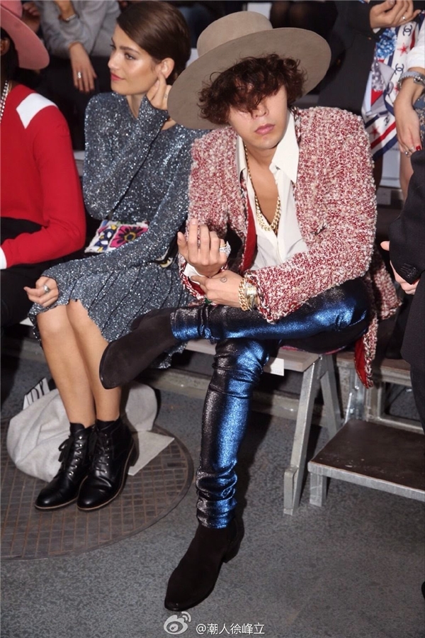 
Đúng với chủ đề womenswear, G-Dragon thể hiện sở thích ăn mặc theo phong cách unisex thường thấy khi kết hợp áo khoác tweed, quần ánh kim xanh và ankle boots.