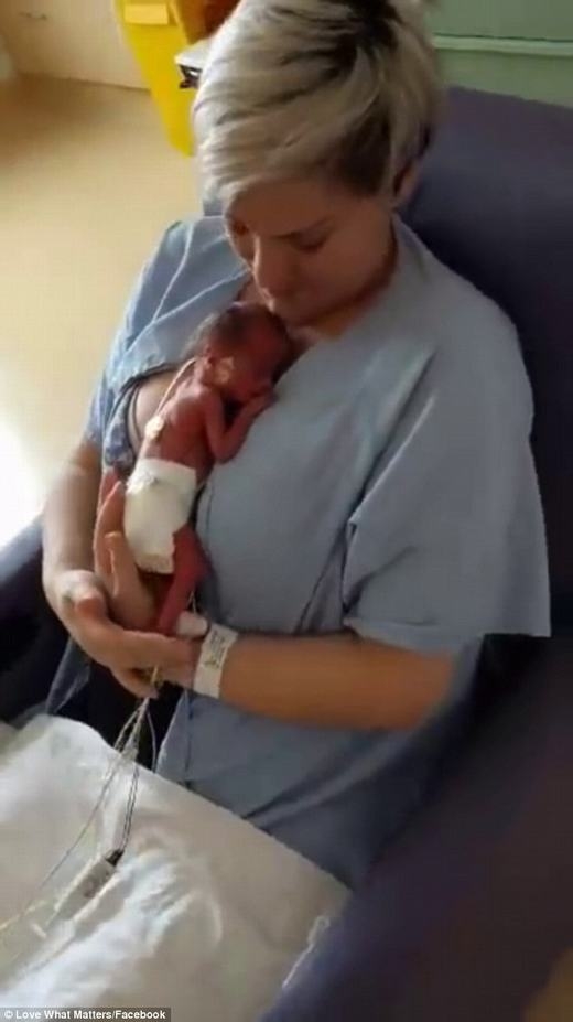 
Em bé đang được mẹ ôm vào lòng lấy hơi ấm. (Ảnh: Chụp màn hình)
