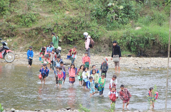 
Những đứa trẻ cấp một tội nghiệp phải cùng nhau băng qua sông để đi học trong lúc phải tay xách nách mang nào là cặp sách, tập vở cùng đồ ăn trưa, giày dép. (Ảnh: Internet)