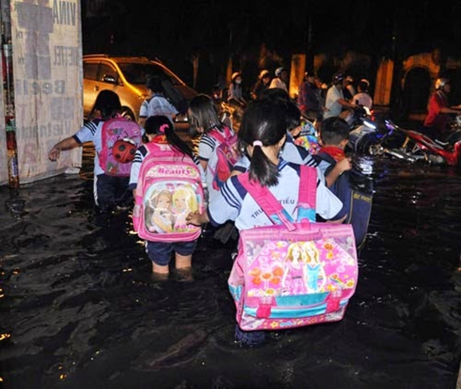 
Các em cấp một phải lội qua nước mưa ngập lút đầu gối để ra chỗ bố mẹ đang đậu xe chờ đón về. (Ảnh: Internet)