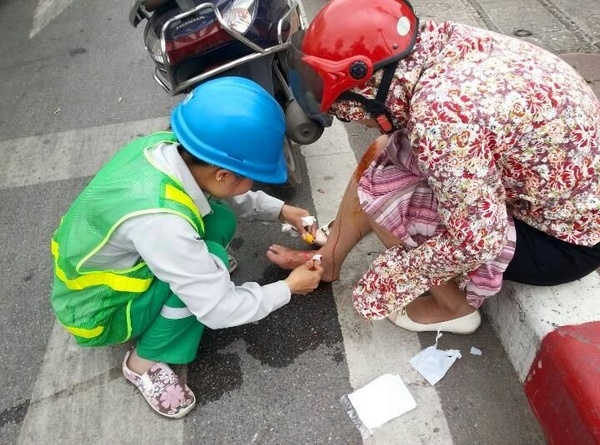 
Chị công nhân vệ sinh môi trường giúp người bị nạn sơ cứu vết thương. Nguồn ảnh: Hòa Phạm