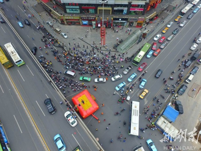 
Người thanh niên leo lên cột đèn giao thông với ý định tự tử thu hút sự chú ý của rất nhiều người. (Ảnh: Hunan Daily)