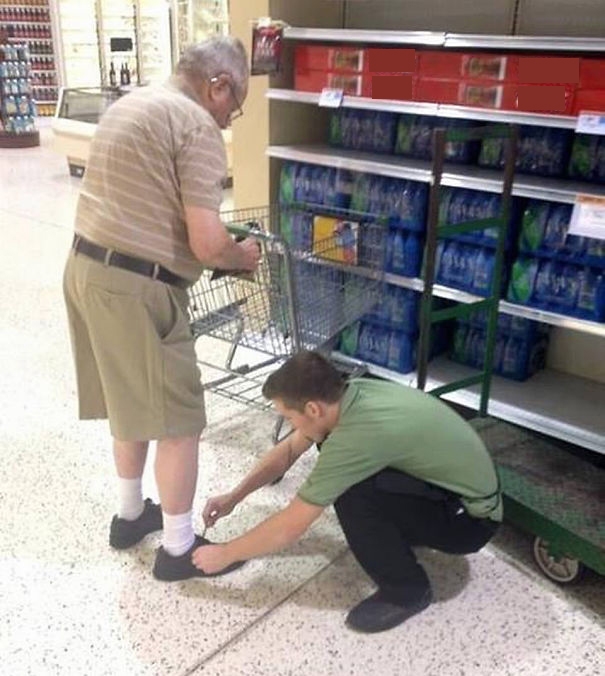 
Một nhân viên siêu thị buộc lại dây giày cho cụ già.