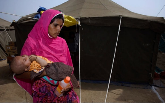 
Người phụ nữ đang bế đứa con gái bị ốm Afsana Din rời khỏi trại y tế cứu trợ lũ lụt.