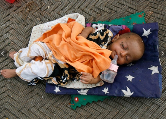 
Nandni, 11 tháng tuổi đang ngủ trong khi mẹ cô bé đi chuẩn bị bữa tối tại trại cứu trợ lũ lụt quân đội Pakistan.