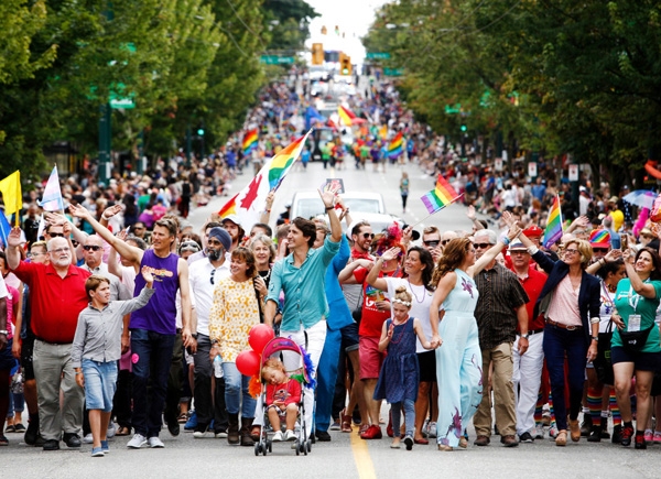 
Thủ tướng Justin Trudeau giơ tay vẫy chào trong khi đi bộ với gia đình anh ấy tại Vancouver Pride Parade.
