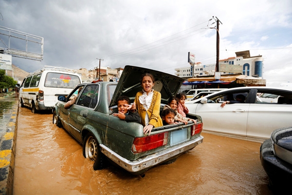 
Trẻ em ngồi trong cốp xe trên đường phố bị ngập lụt ở Sanaa, Yemen.