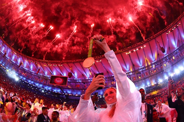 
Một nữ vận động viên đang hào hứng chụp lại huy chương của cô khi pháo hoa nổ rực trời trong lễ bế mạc Olympic 2016 ở Rio de Janeiro, Brazil.