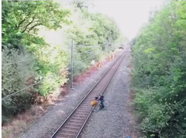 
Một người đàn ông đang cố dắt xe đạp qua đường ray. (Ảnh: Cắt clip)