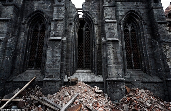​Hình ảnh một đống đổ nát với chiếc ghế và những tấm ván gỗ nằm phía trước một nhà thờ bị tàn phá nặng nề.