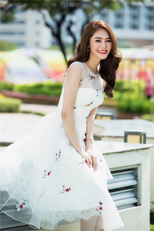 
Linh Chi như nàng công chúa bước ra từ thế giới cổ tích với chiếc váy trắng xòe ngang gối kết hợp họa tiết hoa màu đỏ nổi bật, thu hút của nhà thiết kế Đỗ Long.